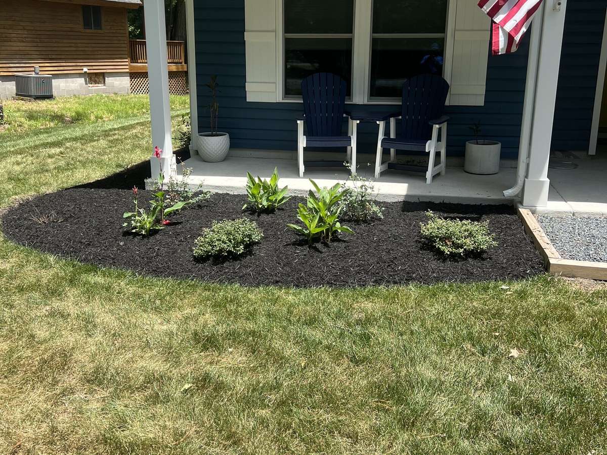 Navy house with American flag and fresh mulch bed