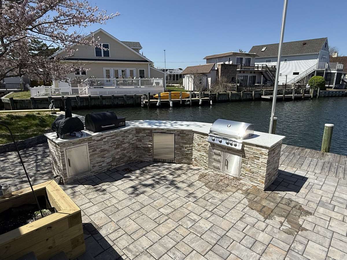 Waterfront outdoor kitchen with stone veneer and paver patio